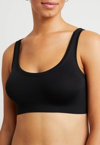 Svart sportbh gjord av mjukt, stretchigt tyg. Har en rundad halsringning och breda axelband. Enkelt design med en sömlös finish.