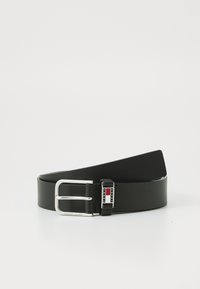 Zwarte leren riem met een glanzende afwerking. Heeft een zilveren metalen gesp met een logo en kleuraccenten in rood en blauw. Glad van structuur.