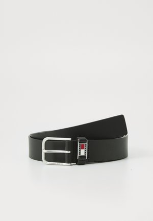 Cinto de couro preto com acabamento brilhante. Apresenta uma fivela de metal prateado com um logótipo e detalhes em vermelho e azul. Textura suave.