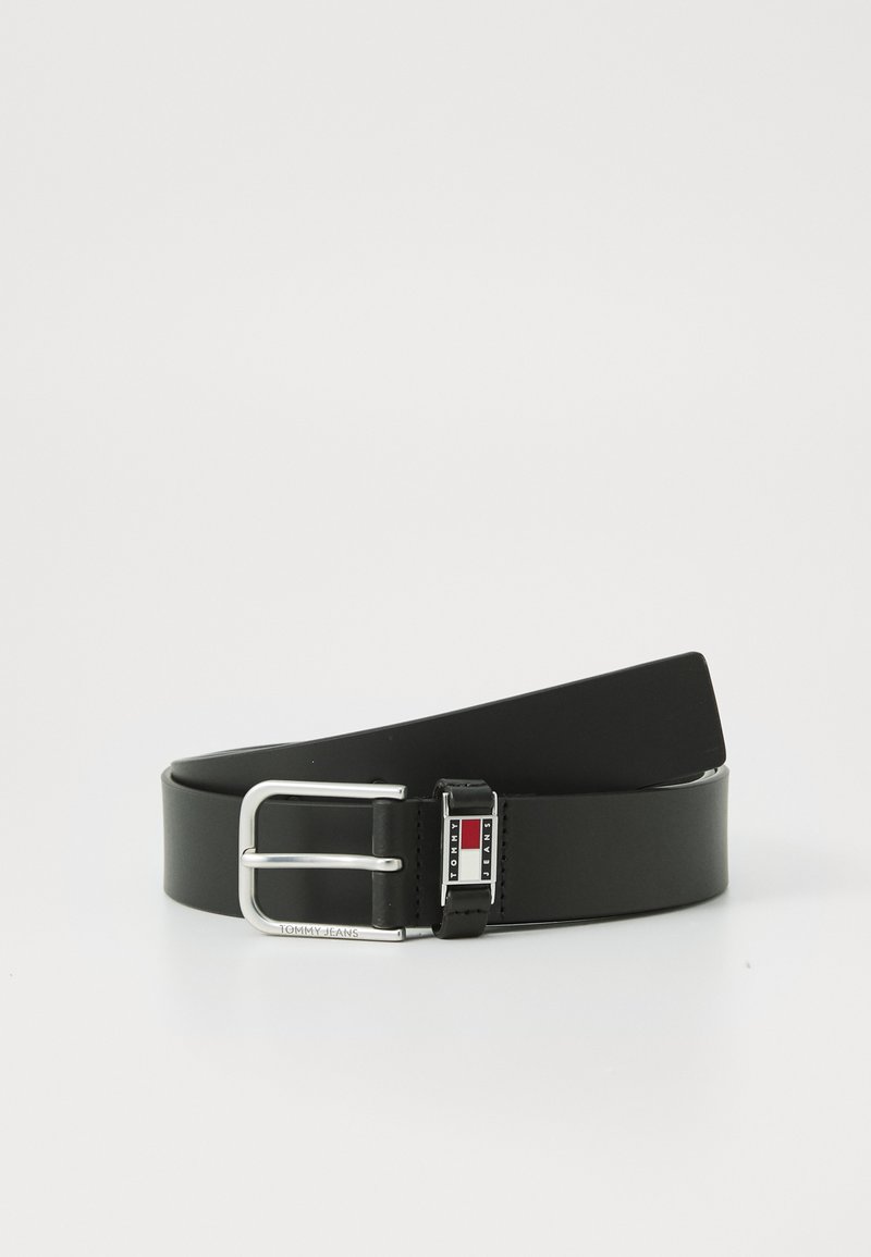 Zwarte leren riem met een glanzende afwerking. Heeft een zilveren metalen gesp met een logo en kleuraccenten in rood en blauw. Glad van structuur.