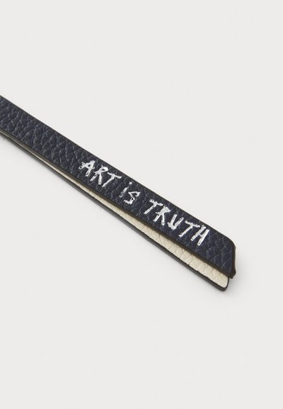 Narrow leather strip in navy blue with a textured surface, featuring the phrase "ART IS TRUTH" embroidered in white.