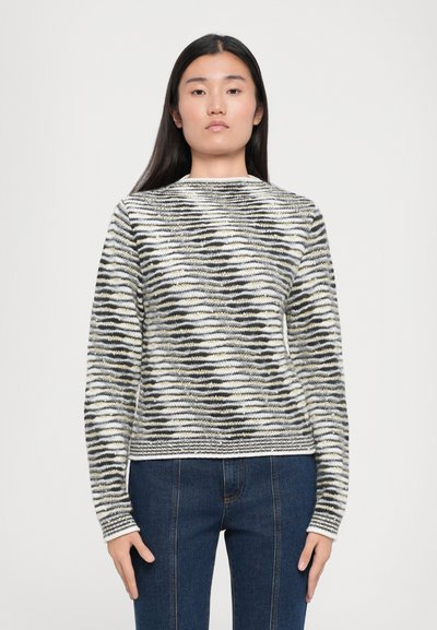 Der gestrickte Pullover weist ein Wellenmuster in Schwarz, Weiß und Gelb auf. Er hat einen runden Ausschnitt, lange Ärmel und eine taillierte Form.