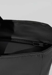 Svart tygväska med en strukturerad yta, toppdragkedja och ett slätt, fodrat inre. Minimalistisk design med förstärkta sömmar.