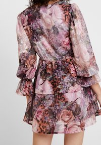 Blommönstrad klänning med genomskinligt tyg, volangärmar, lagerdesign, med rosa rosor och leopardaccent i olika nyanser.