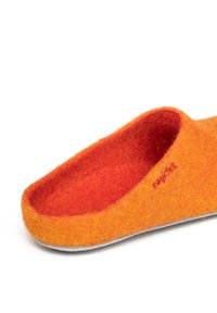 Orange felt slipper with a slightly curved shape, featuring a soft interior lining and a gray outsole. Branding is stitched in red.