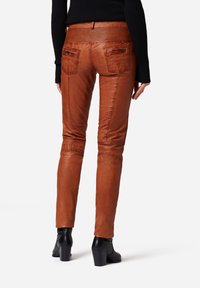 Bruine leren broek met een slim fit, voorzien van een geribbelde tailleband en achterzakken. Draag het met zwarte hakken enkellaarzen.