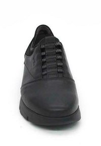 Zapato de cuero negro con un panel frontal elástico y una puntera redondeada suave. Suela de goma plana, diseño de media caña y acentos minimalistas.