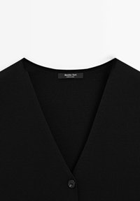 Cardigan nero a V con un solo bottone e un'etichetta "Massimo Dutti" cucita all'interno del collo.