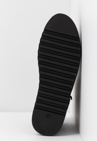 Semelle de chaussure en caoutchouc noir avec des rainures horizontales, un bout légèrement arrondi et un numéro de taille imprimé "37" près du talon.