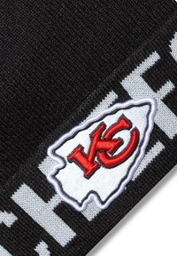 Musta neulepipo, jossa on brodatu valkoinen ja punainen logo, joka muistuttaa osavaltion ääriviivoja ja jossa on 'KC'-alkukirjaimet, harmaan tekstin reunustamana.