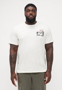 Lichtcrème T-shirt met korte mouwen van katoen, met een bloeiende grafiek in roze en groen op de linkerborst.