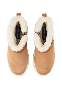 Tan-Farben Wildleder-Stiefeletten mit einem weißen Kunstfellkragen und -futter. Gummisohlen mit strukturiertem Muster; verfügt über ein kleines Lederschild.