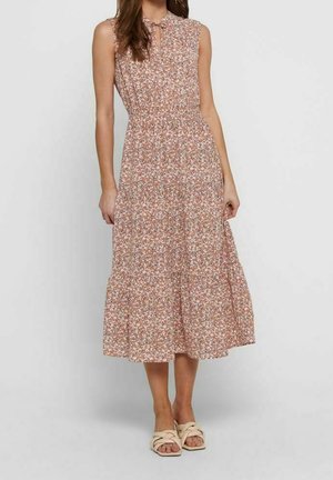 Sukienka midi bez rękawów w różowo-biały kwiatowy wzór, z marszczoną talią i wiązaniem przy dekolcie, noszona z beżowymi wiklinowymi sandałami na płaskim obcasie.