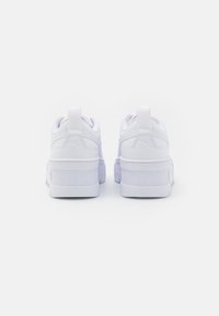 Vita sneakers med en slät texturerad ovandel, förstärkt häl och tjock gummisula med subtil branding på baksidan.