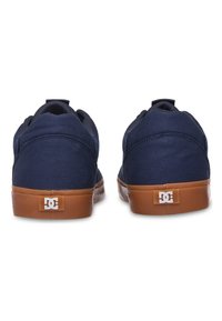 Granatowe płócienne trampki z beżowymi gumowymi podeszwami, wyposażone w tylną naszywkę z logo. Niskoprofilowy krój posiada wyściełany kołnierz dla wygody.