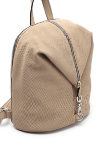Mochila perforada beige con forma redondeada, que presenta un cierre negro y acentos de hardware plateados. Material ligero con un acabado texturizado.