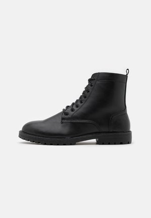 Black leather lace-up ankle boot with rugged sole, round toe, and pull tab at heel, shown in side profile on white background.