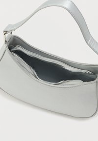 Gaišpelēka rokassoma ar gludu apdari, kas aprīkota ar vienu plecu siksnu un divām rāvējslēdzēju kabatām. Iekšējā auduma krāsa ir tumšpelēka.