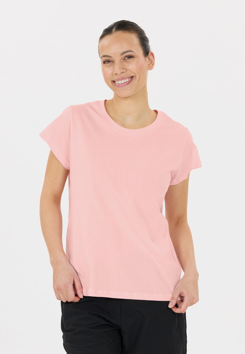 Lichtroze, kortom, katoenen T-shirt met een ronde hals en een relaxte pasvorm, gedragen met donkere shorts; gladde textuur, casual ontwerp.