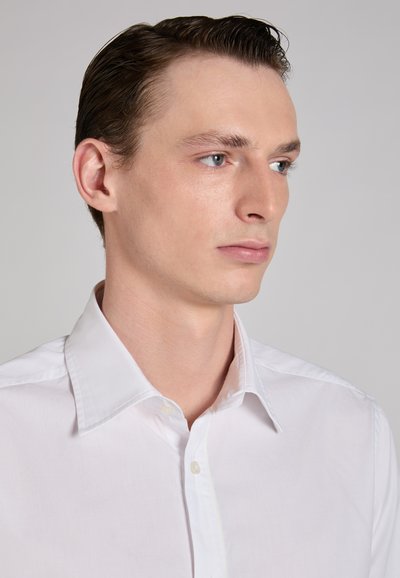 Wit katoenen overhemd met een klassieke kraag, een gladde textuur en knoopsluiting aan de voorkant. Heeft een getailleerde pasvorm en minimale details.