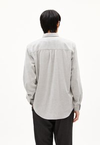 Lichtgrijs langengereg shirt met een knoopsluiting, enkele rugnaad en een afgeronde zoom, gemaakt van gestructureerde stof.