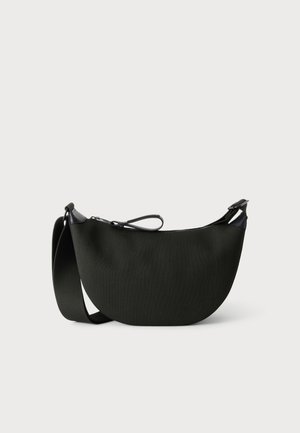 Black half-moon shaped crossbody bag with wide adjustable strap and zipper closure on a plain light background.
