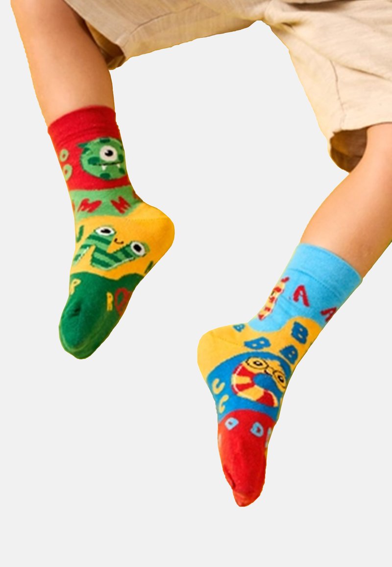 Felgekleurde sokken: een met groene en rode accenten met cartoonfiguren, de ander in blauw en geel met verschillende letters en vormen.