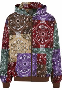 Hooded zip-up jacket in a patchwork design featuring red, purple, green, brown, and beige floral patterns with white accents and brown cuffs.