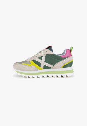 Zapatillas deportivas que combinan materiales en tonos verde, beige y rosa, con un upper de ante texturizado, suela de goma y acentos en amarillo contrastante.
