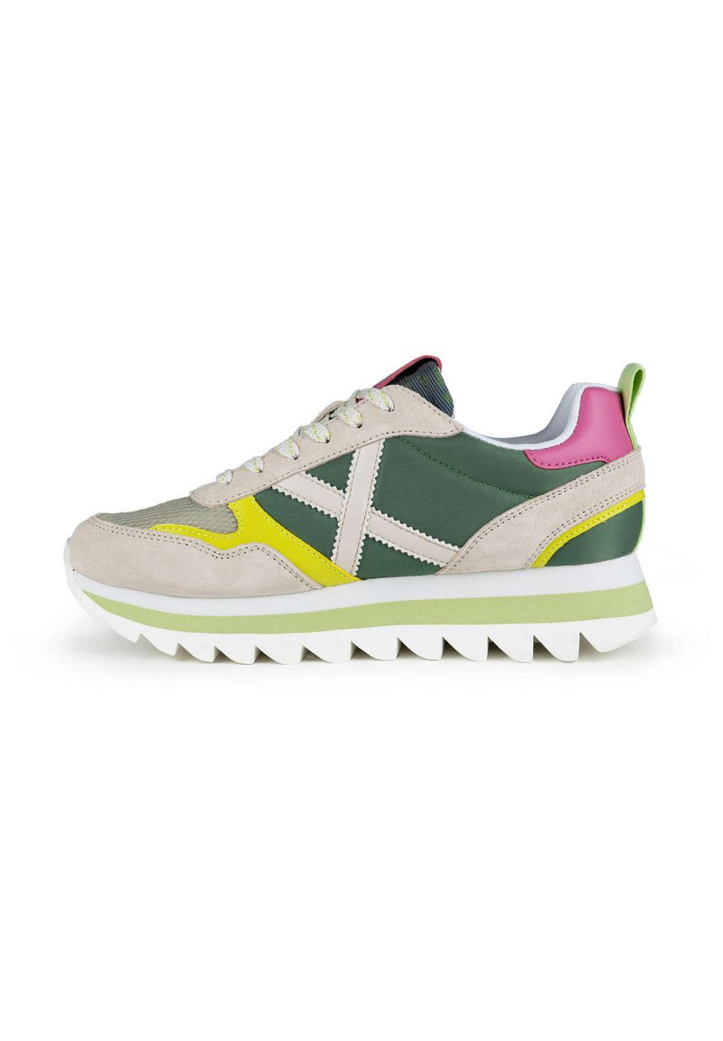 Zapatillas deportivas que combinan materiales en tonos verde, beige y rosa, con un upper de ante texturizado, suela de goma y acentos en amarillo contrastante.