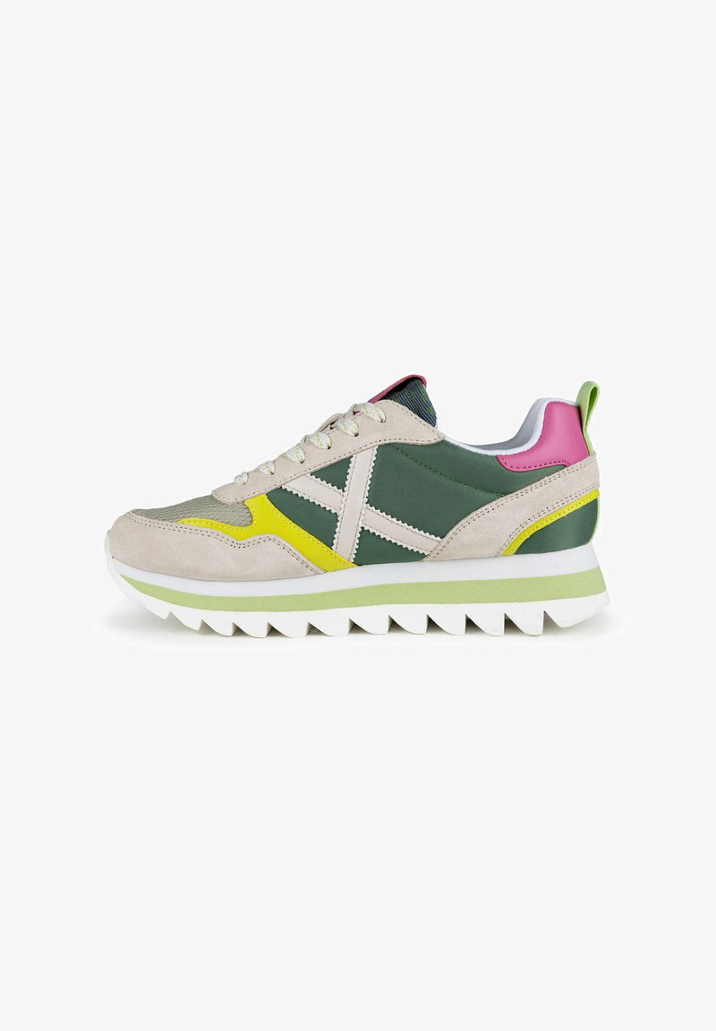 Zapatillas deportivas que combinan materiales en tonos verde, beige y rosa, con un upper de ante texturizado, suela de goma y acentos en amarillo contrastante.