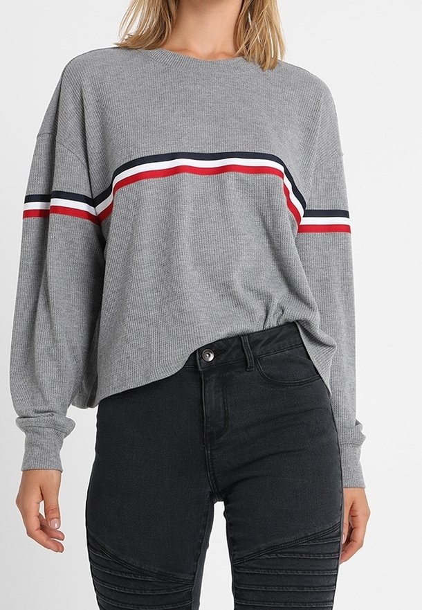 Pull gris à manches longues en maille côtelée avec un motif de rayures horizontales rouge, blanc et marine. Assorti à un jean skinny noir texturé.