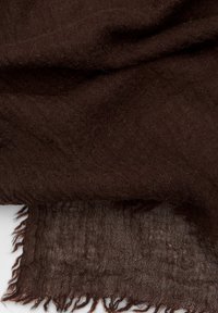 Tessuto intrecciato marrone con una texture morbida, caratterizzato da bordi sfilacciati e un'apparenza grezza e naturale. Nessun motivo o hardware distintivi visibili.