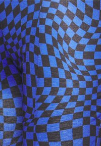 Um tecido padronizado em azul e preto apresenta um design de tabuleiro de xadrez distorcido, criando uma textura visualmente dinâmica com quadrados alternados.