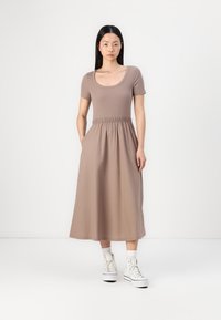 Prune midi kleit lühikeste varrukatega, ümmargune kaelus, elastne talje, küljetaskud ja voolav seelik. Kombineeritud valgete kõrgete tennistega.