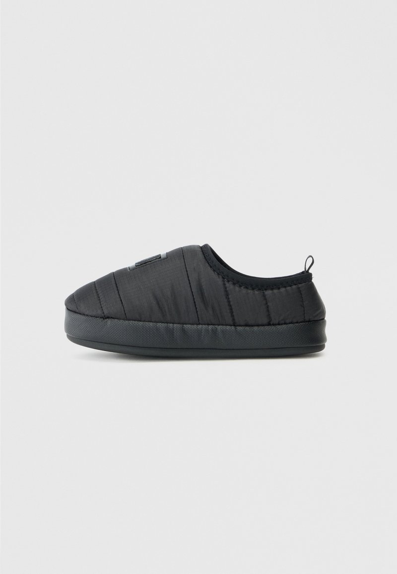 Zapatos negros tipo slip-on con parte superior de nailon acolchado, puntera redonda y suela de goma texturizada, con una pequeña lengüeta trasera para facilitar su uso.