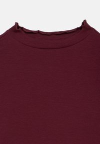 Bordó bordázott felső texturált anyagból. Kerek nyakkivágással, fodros széllel, simán kivitelezett varrásokkal. Nincsenek további részletek.