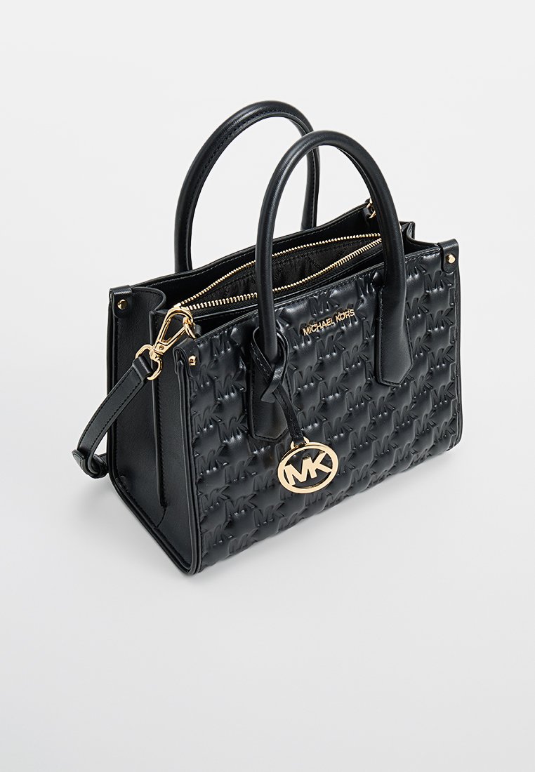 Sac à main en cuir noir avec une texture matelassée et un motif de logo en relief, des poignées doubles, des éléments en métal doré et une fermeture zippée sur le dessus.