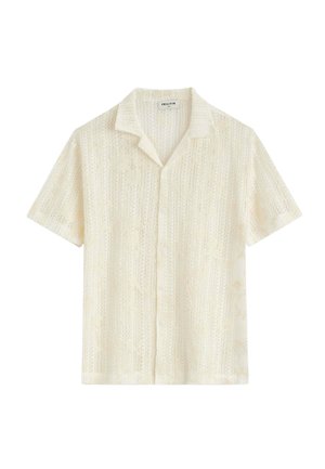 Chemise crème à manches courtes avec boutons, motif texturé subtil et col ouvert.