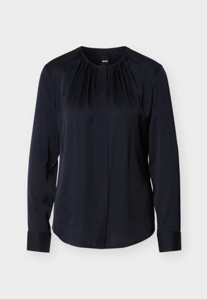 Blusa blu navy con maniche lunghe, scollo plissettato e chiusura con bottoni. Tessuto liscio con polsini e vestibilità leggermente sagomata.