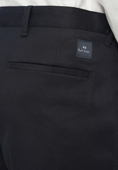 Tmavomodré nohavice s jemnou rybej kostnej textúrou, s jedným zadným vreckom a značkovou štítkom s nápisom "PS Paul Smith".