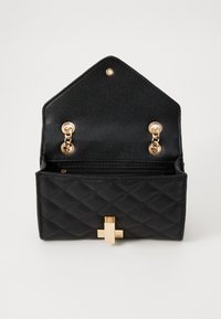 Borsa in ecopelle nera trapuntata con chiusura e dettagli in metallo dorato, dotata di un'apertura a triangolo strutturato e tasca interna.
