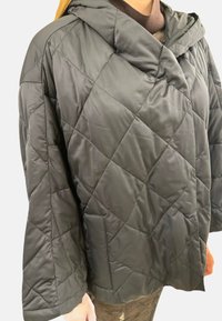 Veste matelassée noire avec capuche, présentant un motif en losanges, des manches ample, et une texture lisse et brillante. Idéale pour la chaleur.