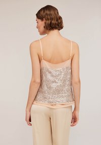 Ärmelloses Oberteil mit einer hellrosa Satin-Vorderseite und einem Rücken, der mit silbernen Pailletten bedeckt ist. Es verfügt über verstellbare Träger und ein geschichtetes Design.