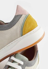 Sneaker mit einer Mischung aus weichem Wildleder in Beige, Pink, Grün und Gelb, einer weißen Gummisohle und kontrastierenden Schnürsenkeln. Sichtbare strukturierte Akzente.