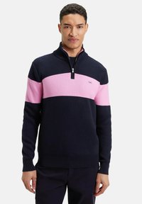 Pull en maille bleu marine et rose avec un col à demi-zip, présentant un design texturé et des blocs de couleur horizontaux. Logo discret sur la poitrine.