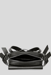 Sac à main en cuir noir avec fermeture éclair, base plate, bandoulières et texture lisse. Dispose de deux compartiments ouverts à l'intérieur.