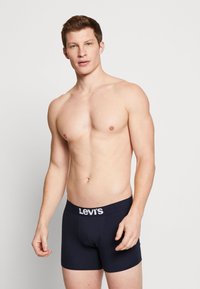 Marineblauwe katoenen boxershorts met een witte "Levi's" logo op de tailleband. Het ontwerp is aansluitend met een gladde textuur en een lengte tot halverwege de bovenbenen.