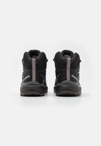 Chaussures de randonnée noires avec une tige en maille texturée, un col rembourré et des accents gris contrastants. Présente un talon renforcé et une semelle antidérapante.