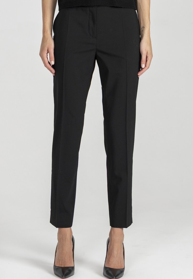 Czarne, dopasowane spodnie o wąskim kroju, gładka tkanina, subtelne detale zakładek, długość 7/8 oraz kieszenie z przodu bez fałd. W połączeniu z czarnymi szpilkami.